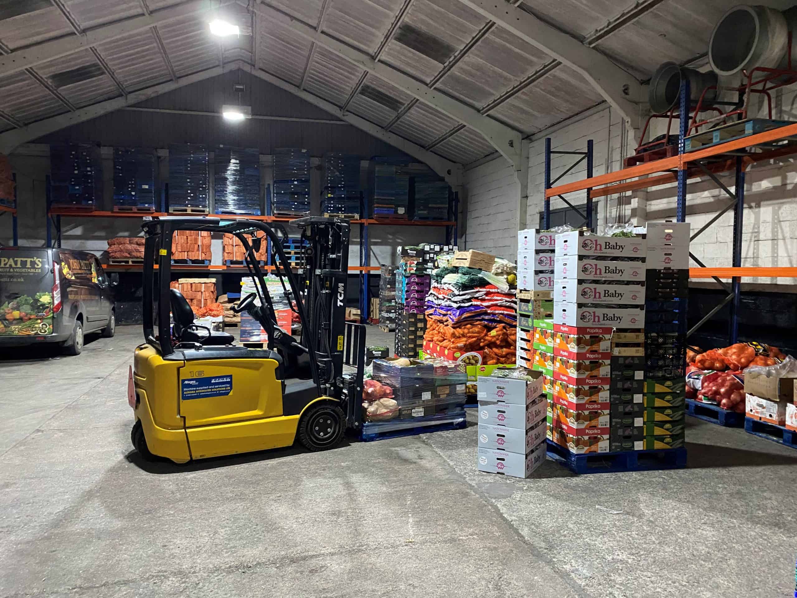 Forklift truck transporting fresh produce in a wholesale warehouse.